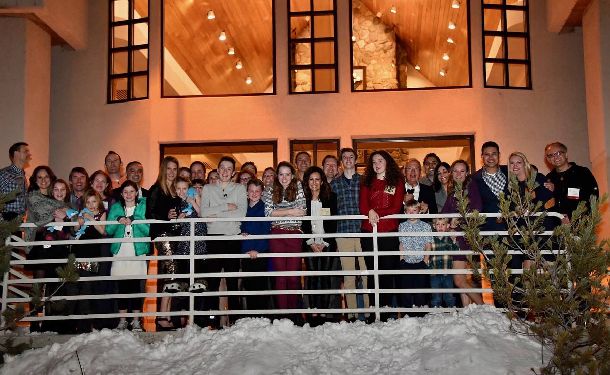 The whole Society gathered on the snowy steps of a timber lodge at night, waving to the camera