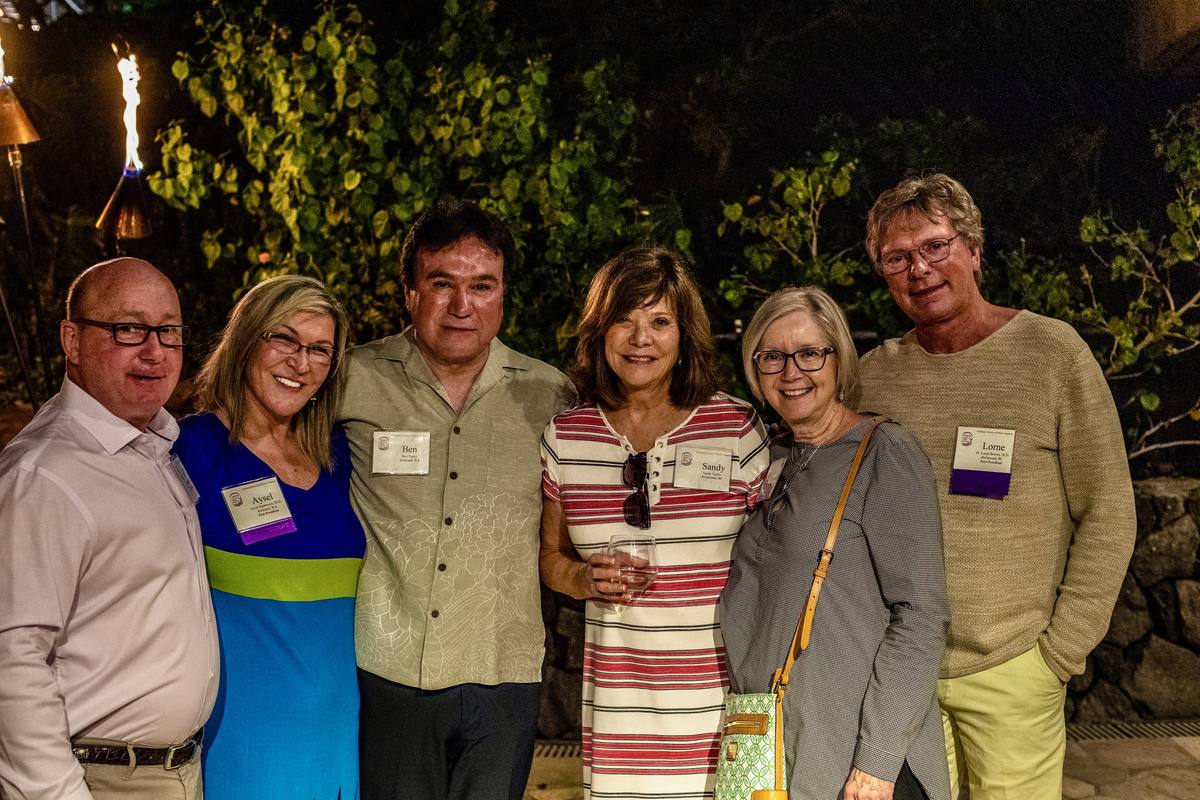 Six people together at an evening reception among tropical plants