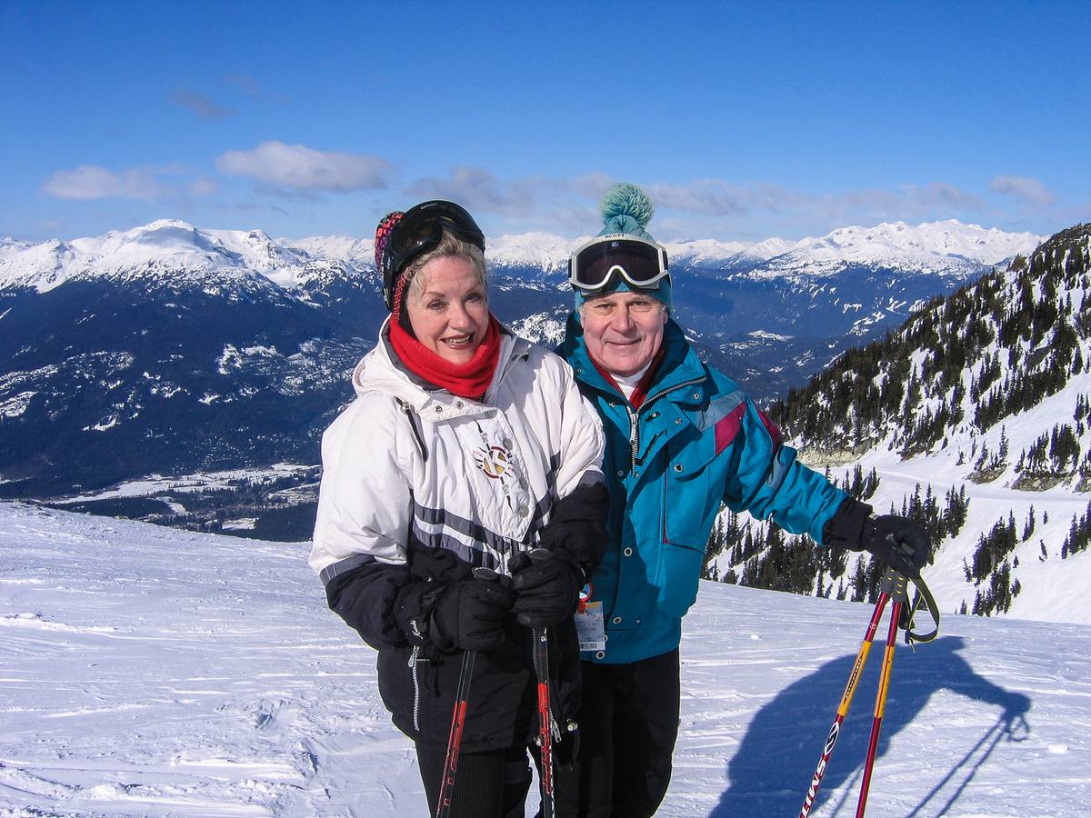 Two skiers on a high run with a panorama of snow-covered peaks behind them