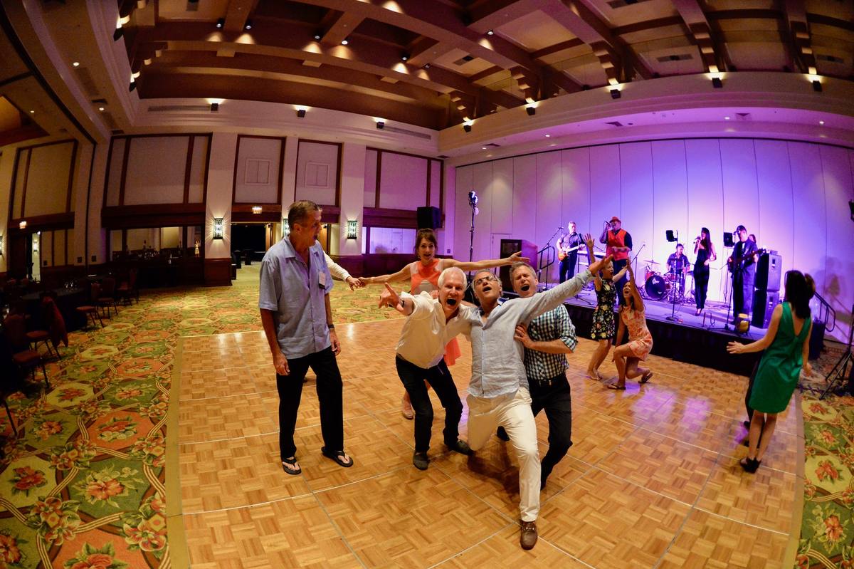 Dancers on a ballroom floor with the band on stage under coloured lights