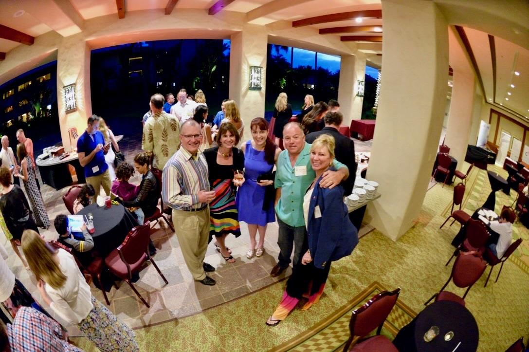 Guests gathered at cocktail tables in an open-sided dining room at dusk