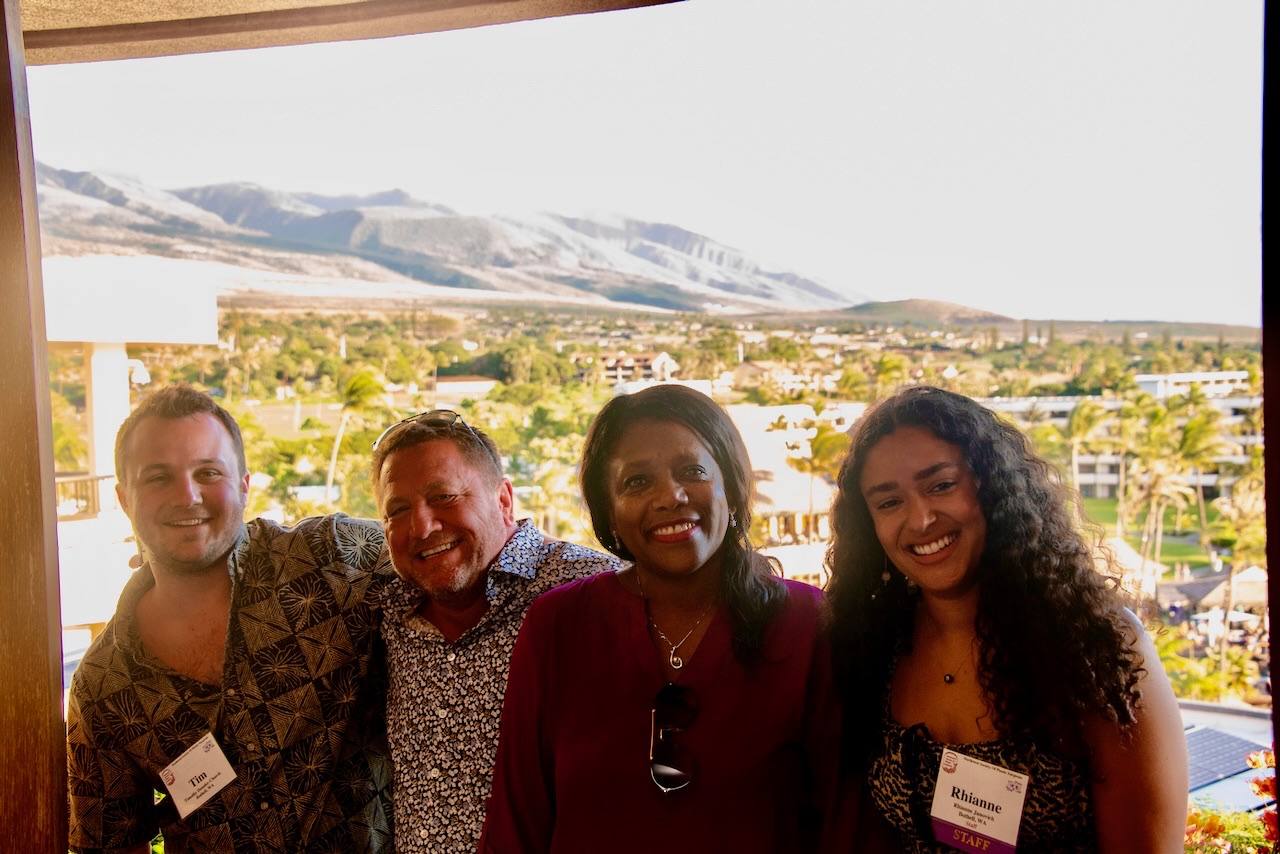 Four attendees on a lanai with the West Maui mountains behind them