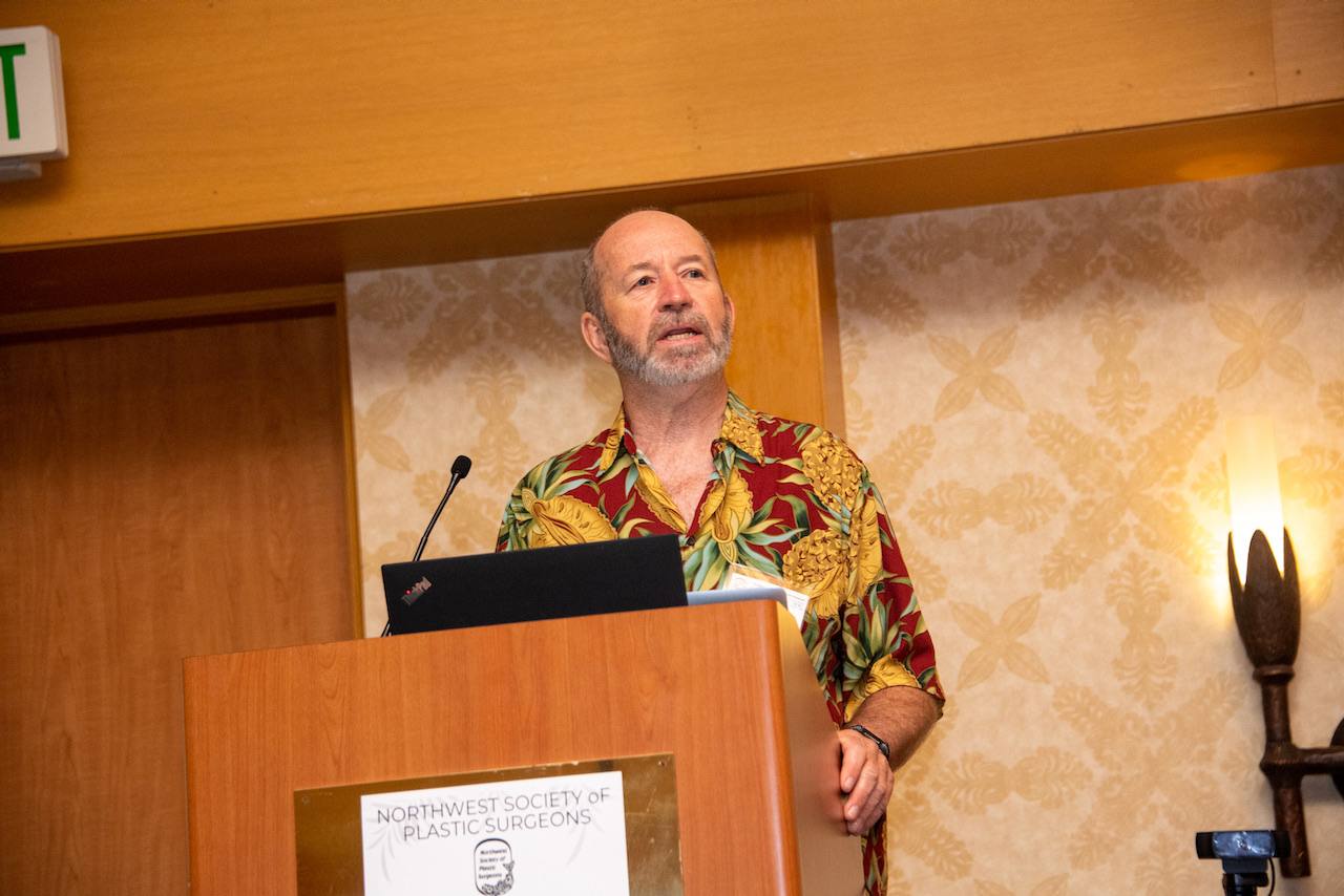 A speaker in an aloha shirt presents from the lectern