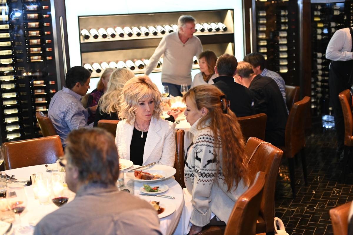 Members at dinner in a restaurant lined with wine racks