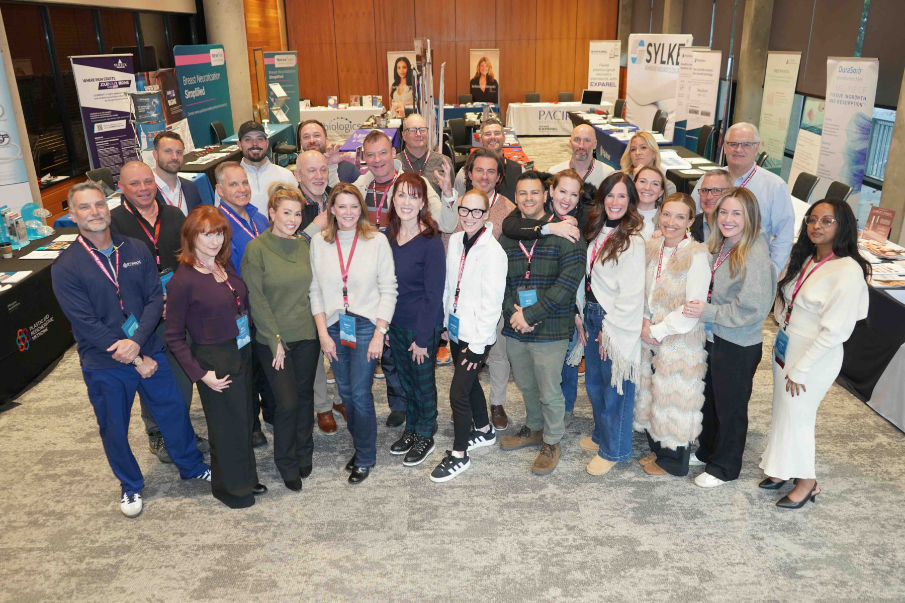 Members and exhibitor representatives pose together in the exhibit hall among the sponsor booths